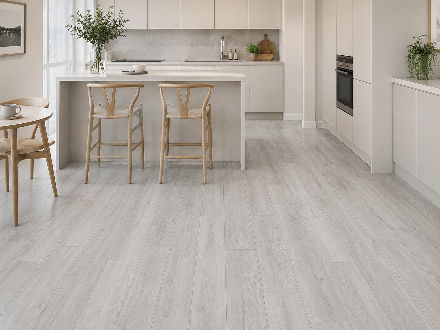 Minimalistička kuhinja sa trpezarijom i laminatom K278 Nevis Oak, svetlim frontovima, ostrvom, svetlim drvenim stolicama i prozračnim skandinavskim enterijerom.